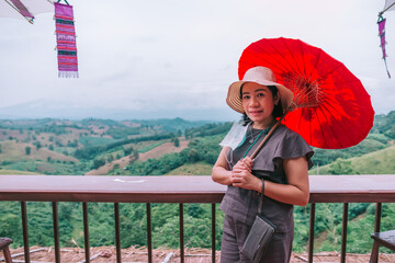 A beautiful asian woman  sitting on balcony and looking at mountains and green