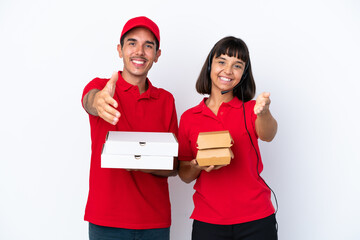 Young delivery couple holding pizzas and burgers isolated on white background shaking hands for closing a good deal