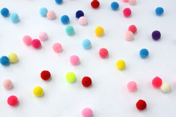 Small colored pom-poms  on white. Fluffy pom-poms for needlework.