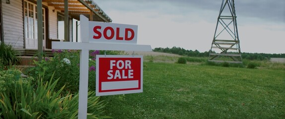 Fototapeta premium For sale sign standing on a lawn in front of an American style house