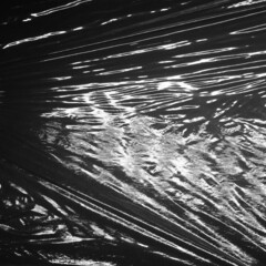 Reflecting light and shadow on creases and pleats in stretched black plastic sheeting