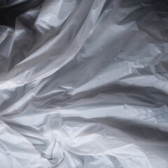 Reflecting light and shadow on creases and folds in scrunched white fabric or plastic sheet
