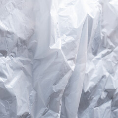 Reflecting light and shadow on creases and folds in scrunched white fabric, paper or plastic sheet