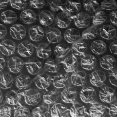 Reflecting light and shadow on creases and tears in plastic bubble wrap sheet, close up
