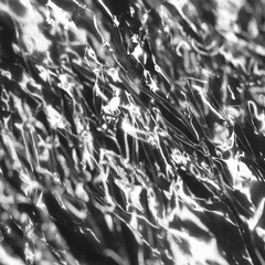 Abstracted shapes of light and shadow on creases and folds in scrunched plastic foil
