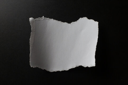 Roughly torn rectangle of white paper on black background