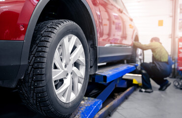 Mechanic changing wheel, replacement of winter and summer tires of modern car