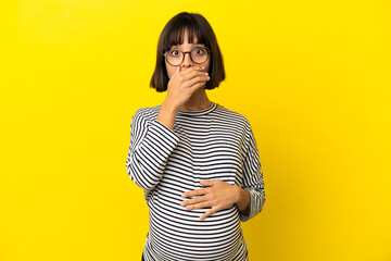 Young pregnant woman over isolated yellow background surprised and shocked while looking right
