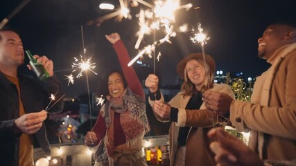 Diverse group of adlut friends dancing with sparklers at a rooftop party in the night time. High quality 4K footage - Powered by Adobe