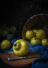 Organic and ripe quinces on a wooden kitchen table Dark mood food photography