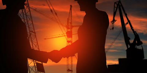 Engineer manager teamwork, silhouette of construction and two business man team Checking hands at working site. agreement .Orange Sunset Shiny Sun Light background. 