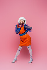 KYIV, UKRAINE - DECEMBER 10, 2020: Smiling asian woman in pop art style holding joystick on pink background