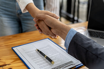 Two businesswomen shake hands after accepting a business proposal together, a handshake is a...