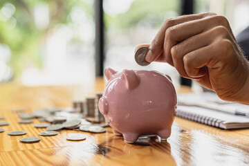 A businessman holding a coin in a piggy bank. Placing coins in a row from low to high is comparable...