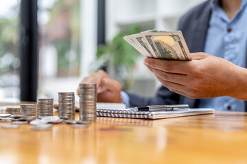 A man is counting his salary dollars to separate expenses, he keeps a monthly account to plan his...