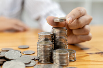 Businesswoman putting a coin on a pile of coins. Placing coins in a row from low to high is comparable to saving money to grow more. The concept of growing savings and saving by investing in stock fun
