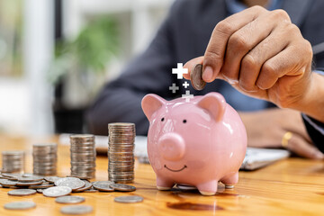 A businessman holding a coin in a piggy bank. Placing coins in a row from low to high is comparable to saving money to grow more. The concept of growing savings and saving by investing in stock funds.