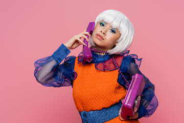 Pretty asian pop art model wrapped in cable talking on telephone isolated on pink