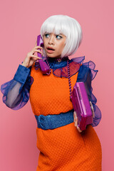 Asian woman in pop art clothes talking on telephone isolated on pink