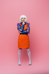 Pretty asian pop art woman in white wig looking at camera on pink background