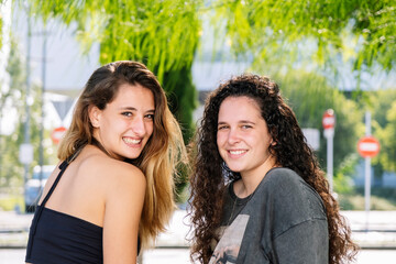 Two girls sitting outdoors and smiling.