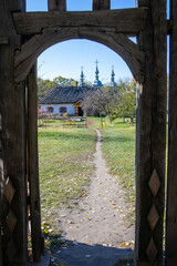 Rural landscape framed by a wooden gate opening. Ethnographical museum