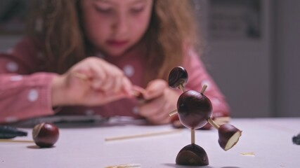 Creative Young Caucasian Girl Making Funny Figure For School Project with Chestnuts and Wooden...