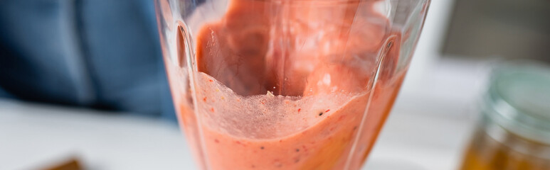 Close up view of fruit smoothie in blender in kitchen, banner