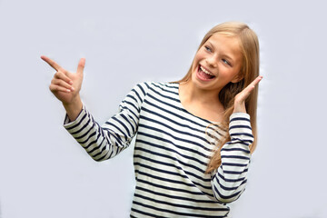TEENAGE GIRL SMILES AND POINTS WITH HER HAND. ISOLATE ON A GRAY BACKGROUND