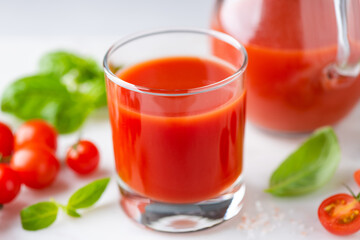 Salted tomato juice in glass on white stone background, closeup view