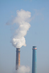 furnace with polluting white smoke on perfect blue sky in background