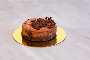 Frozen cake, chocolate cheesecake on a golden backing. Grey background, selective focus, copy space