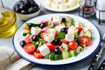 Greek salad with black olives and feta cheese on plate with olive oil dressing, closeup view