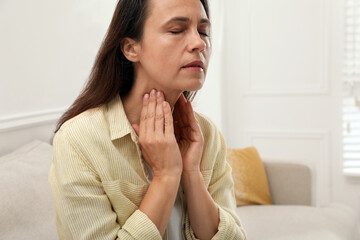 Fototapeta na wymiar Mature woman doing thyroid self examination at home