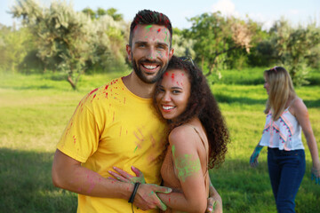 Obraz premium Happy couple covered with colorful powder dyes outdoors. Holi festival celebration
