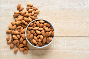 Dried almonds in bowl on a wooden background, table top view with copy space