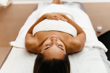 Top view shot of Spa therapist applying scrub salt on young woman back at salon spa. Hands massaging female back with scrub.