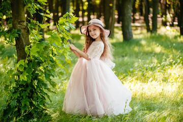 Obraz na płótnie Canvas A young girl in a beautiful dress and hat in nature