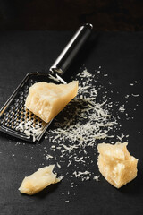 Grated cheese close-up on a dark kitchen table. Chunks of parmegiano cheese on the kitchen table