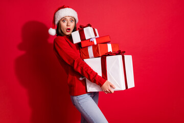 Photo of funky impressed young woman wear ornament sweater carrying noel gifts walking isolated red color background