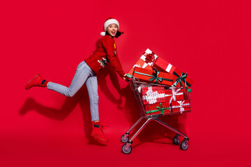 Photo of shiny funky young lady dressed print pullover smiling walking buying noel presents isolated red color background