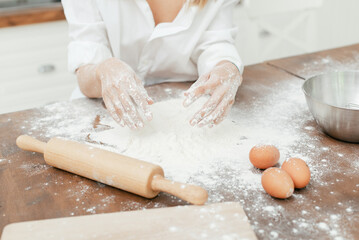 girl in the kitchen sculpts dough hands and table in white flour