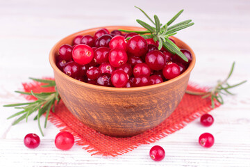 Fresh cranberries in a clay bowl on a white background.
Close-up.