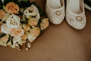 on a vintage armchair there is a bouquet of flowers and wedding shoes with wedding rings.