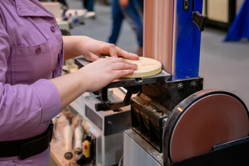Professional woman carpenter hands using belt sander machine, polishing wood product at workshop -...