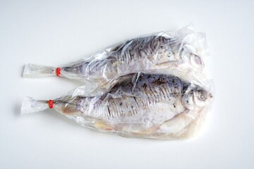 Freshwater Carp, Fish pickled Thai style in plastic wrap on white background, Preserving food homemade by marinating with salt, rice, garlic, herbs and spices, Meat fillets are salty and sour taste.
