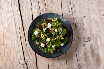 Beetroot salad with feta cheese,lettuce and walnuts on rustic wooden table	
