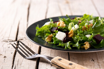 Beetroot salad with feta cheese,lettuce and walnuts on rustic wooden table	
