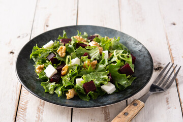 Beetroot salad with feta cheese,lettuce and walnuts on rustic wooden table	
