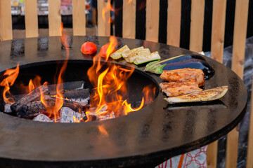 Process of cooking meat steaks, zucchini, eggplant, tomato on grill, brazier at outdoor summer...